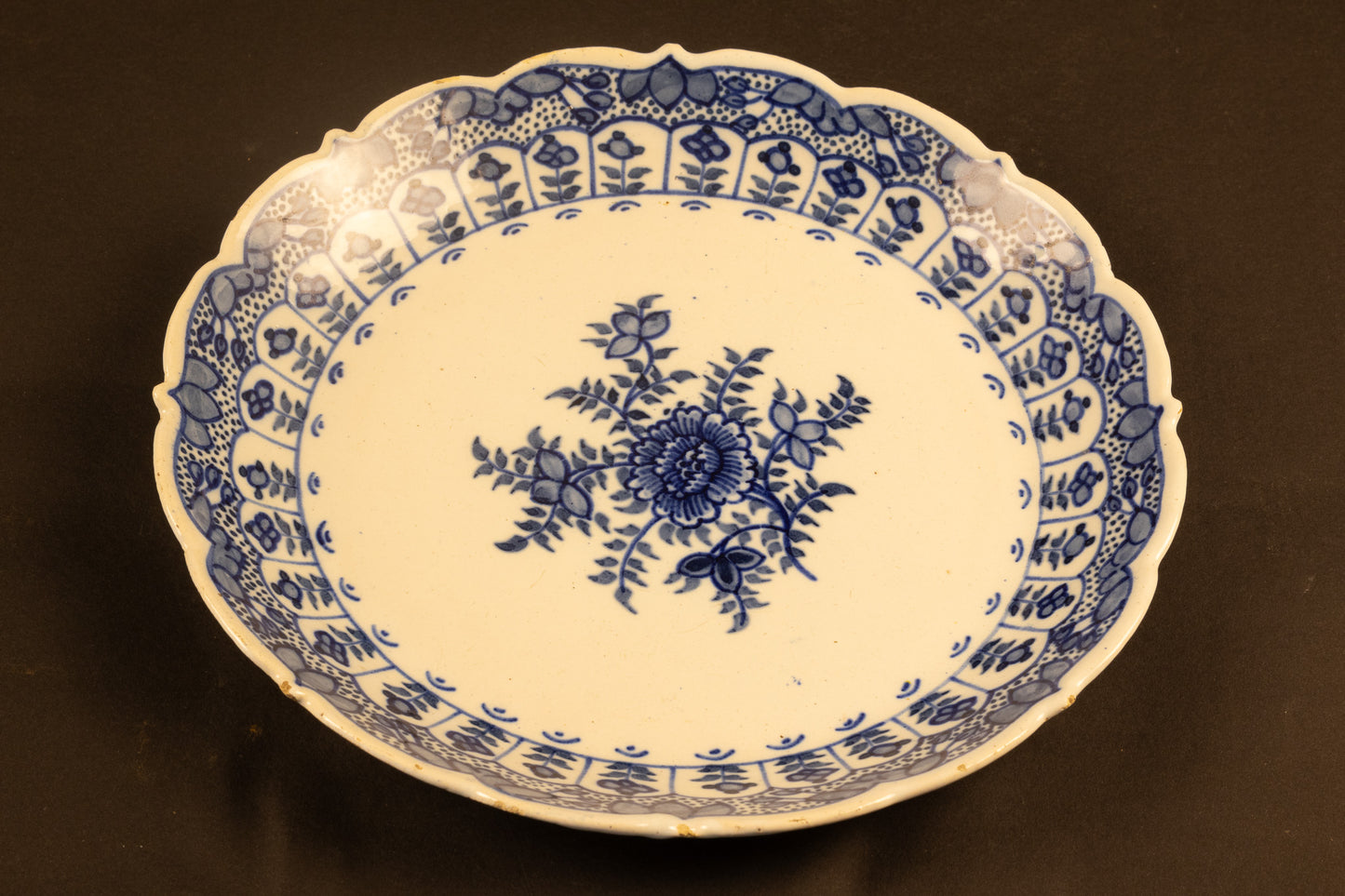 18e-eeuws Delfts blauw aardewerk bord met geschulpte rand en floraal decor